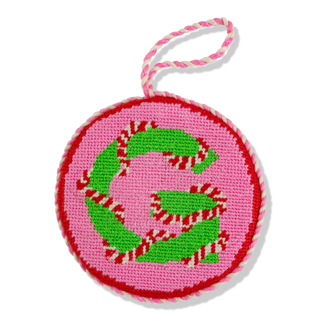Circular pink patch with green letter 'G' and red and white striped border on a white background