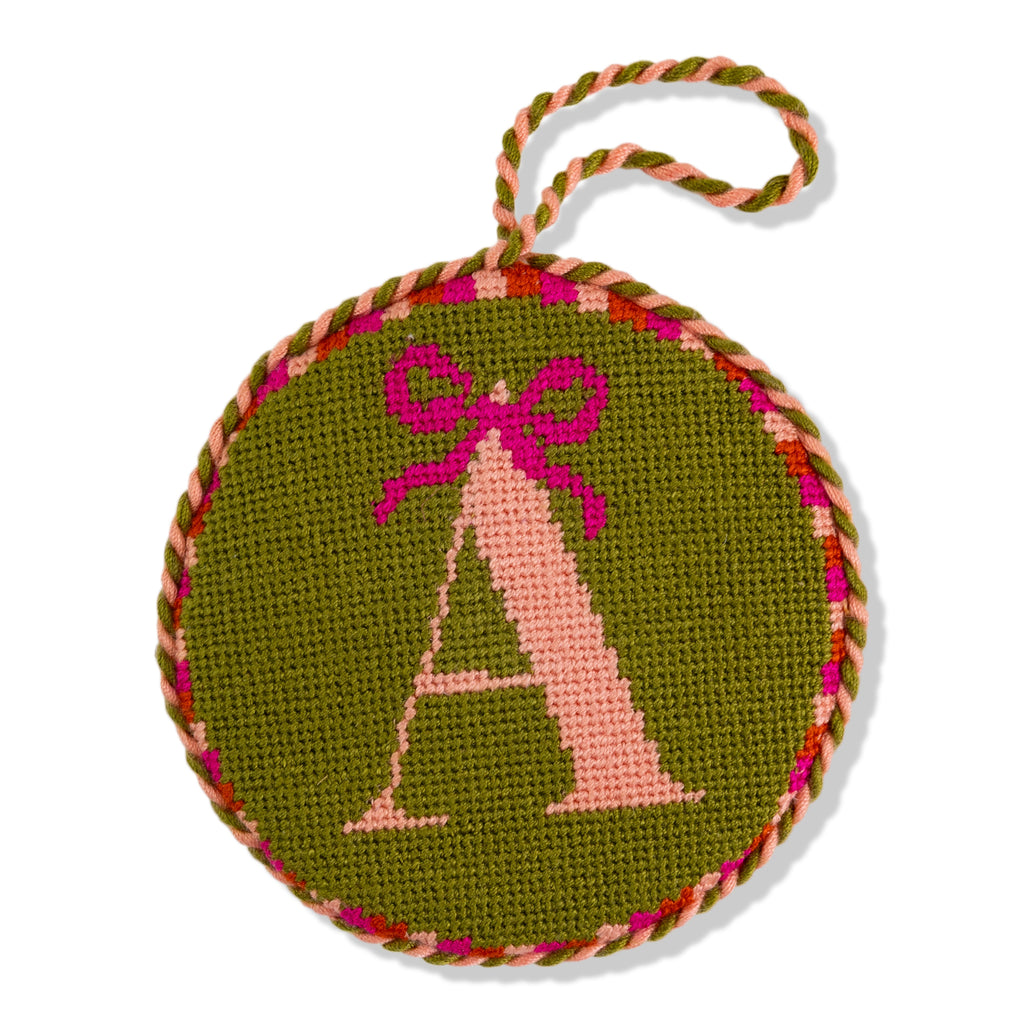 Decorative ornament with letter 'A' and pink bow on a green background