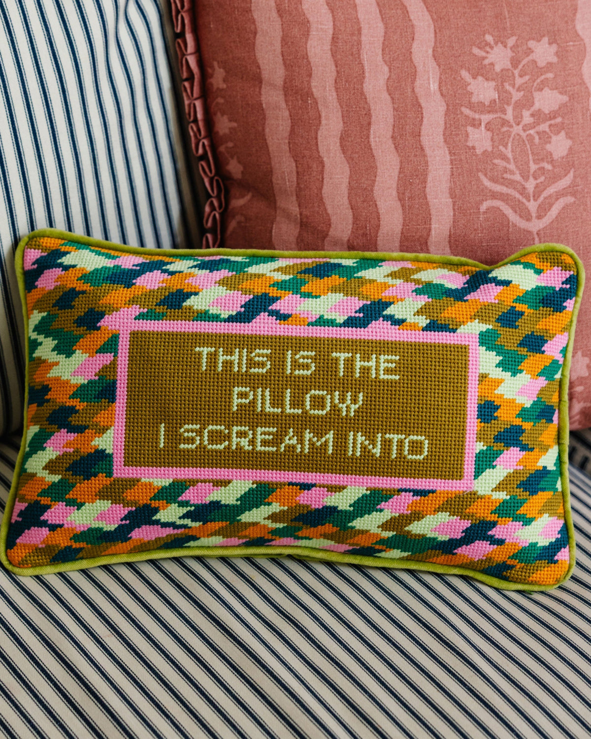 Decorative pillow with geometric pattern and text on a striped sofa