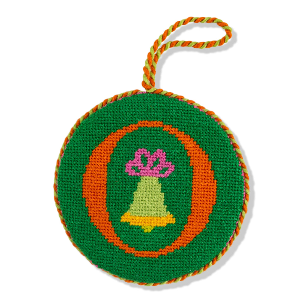 Circular embroidered ornament with a bell and bow design on a green background
