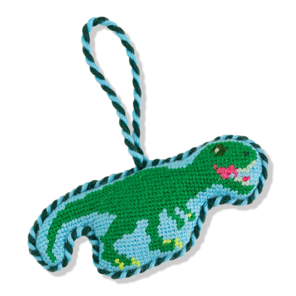 Crocheted dinosaur toy with a rope handle on a white background
