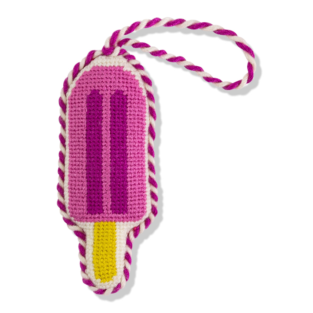 Crocheted ice cream cone toy with pink top, yellow middle, and white bottom on a white background