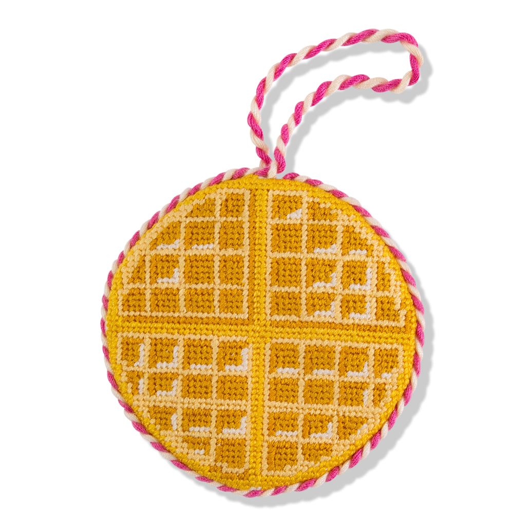 Round yellow object with waffle pattern and pink and white string on a white background
