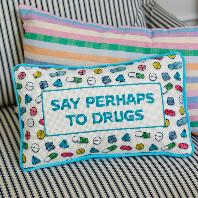 Decorative pillow with 'Say Perhaps to Drugs' text on a striped couch