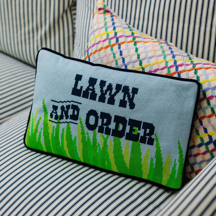 Decorative pillow with 'Lawn and Order' text on a striped sofa