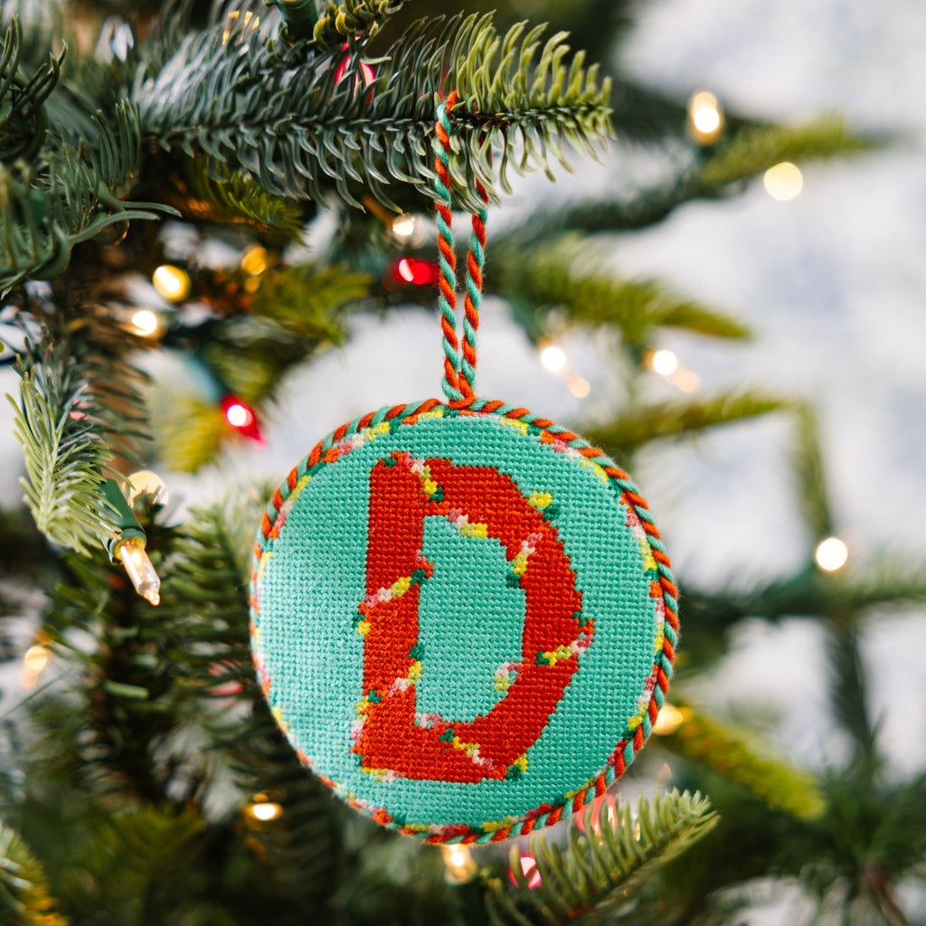 Decorative Christmas ornament with letter 'D' hanging on a tree