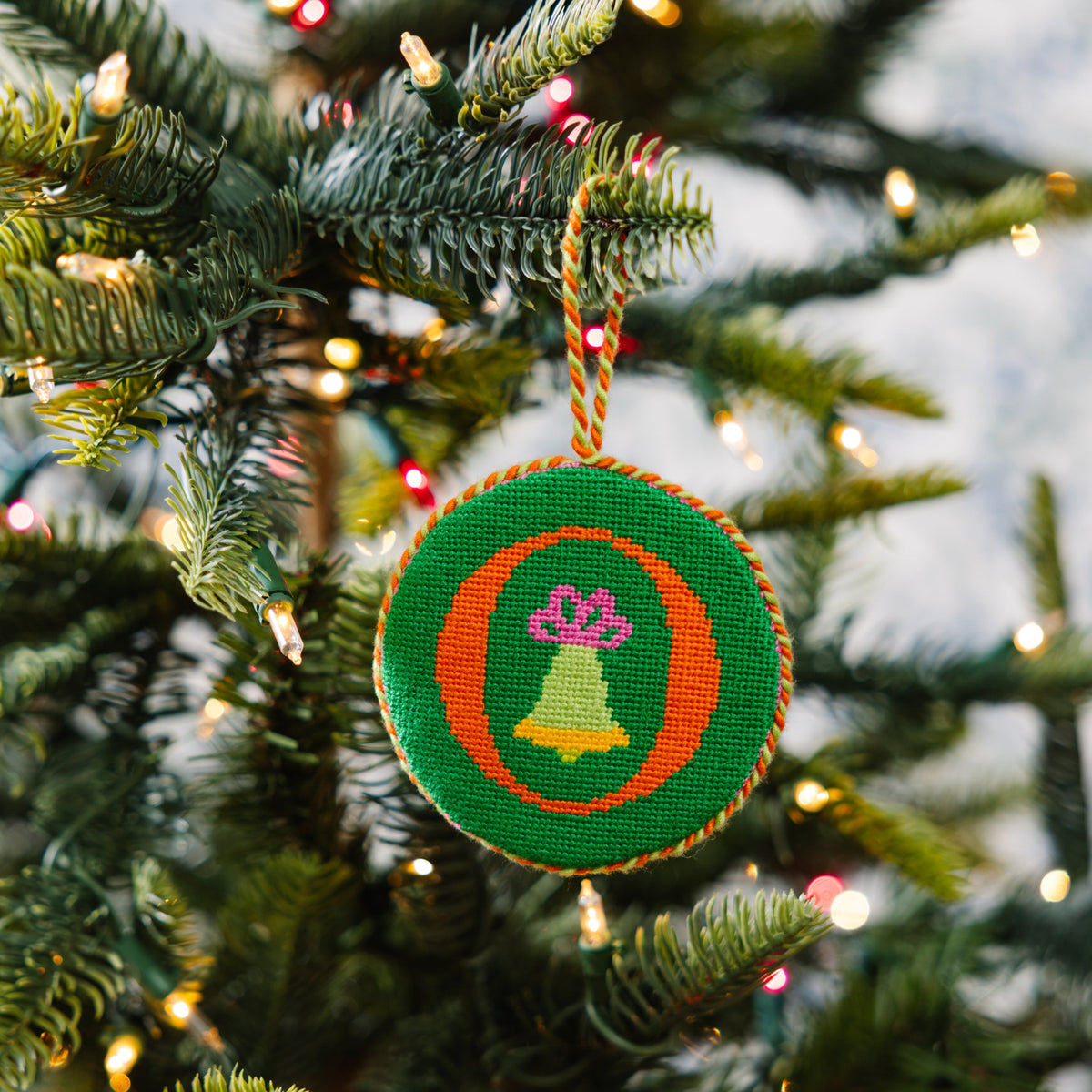 Decorative Christmas ornament with a green circle and bell design on a Christmas tree.