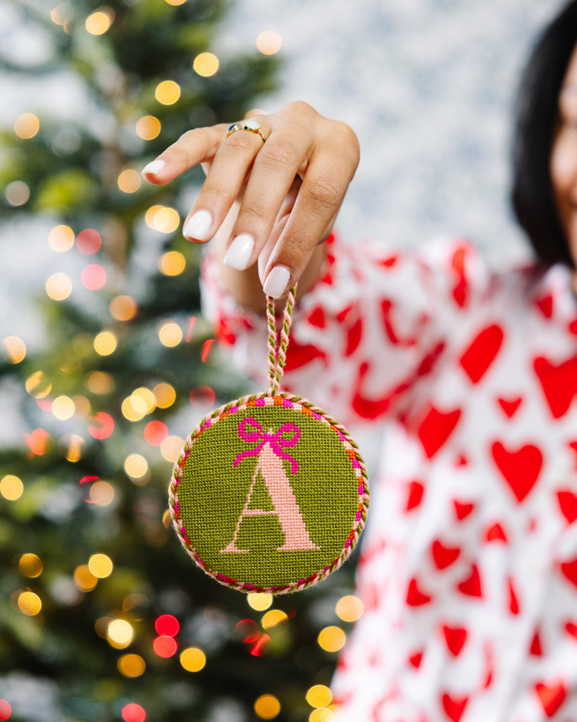 Person holding a Christmas ornament with a tree in the background