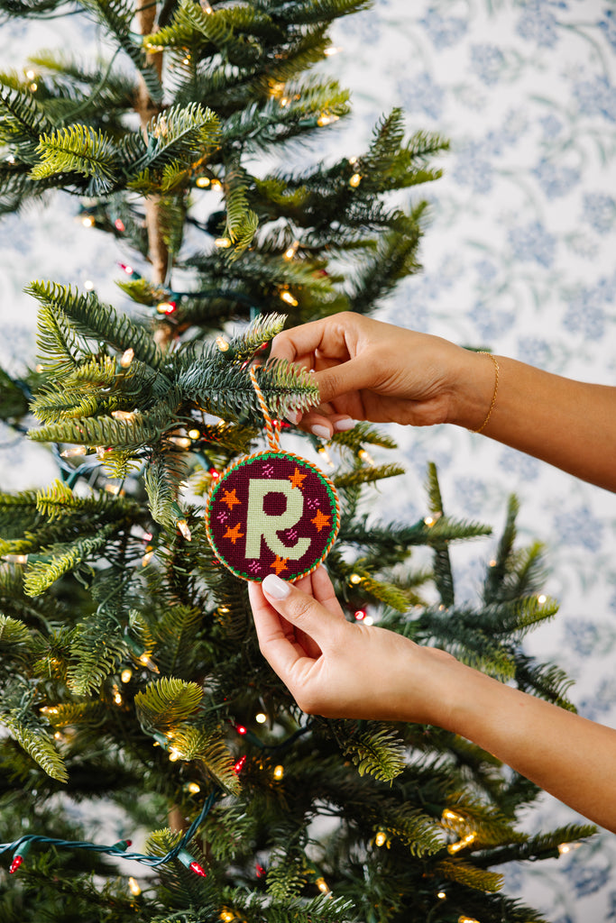 Person decorating a Christmas tree with a ornament featuring the letter 'P'.