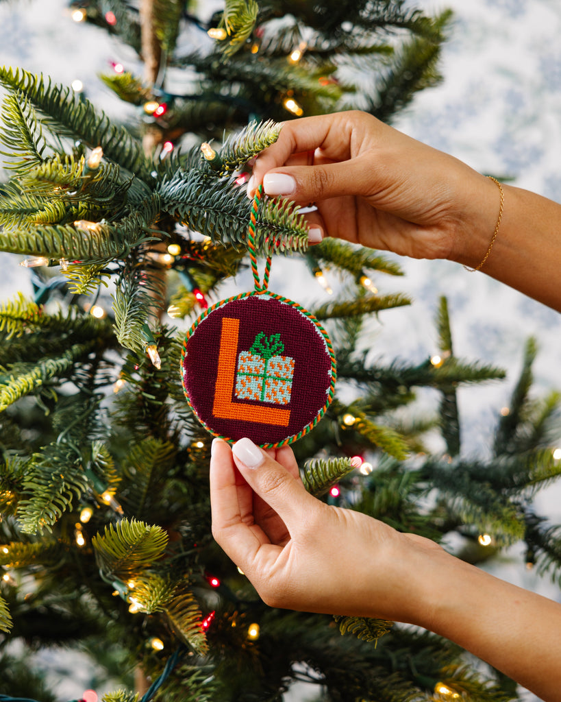 Hand holding a Christmas ornament with a tree in the background