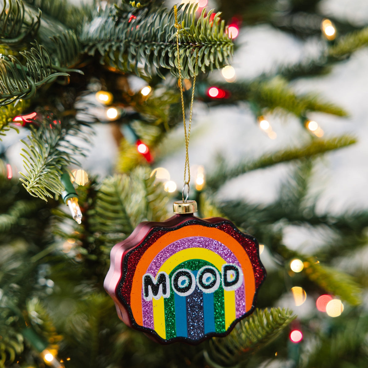 Decorative ornament with rainbow design and 'MOOD' text on a Christmas tree.