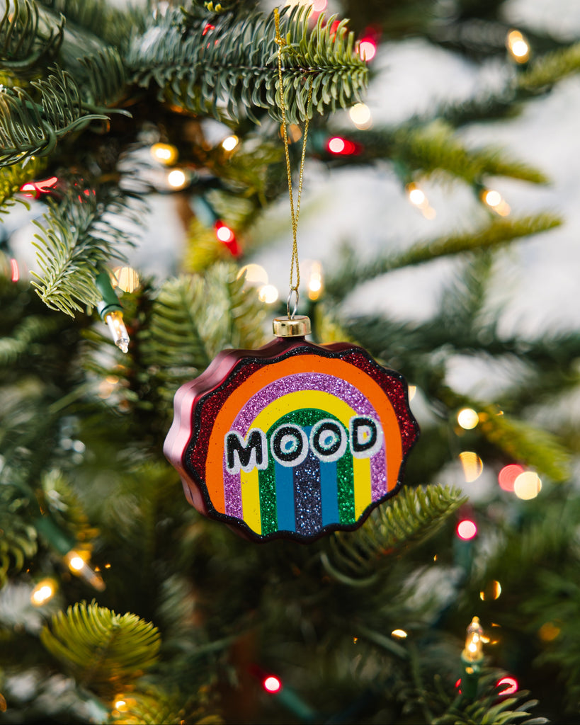 Decorative ornament with rainbow design and 'MOOD' text on a Christmas tree.