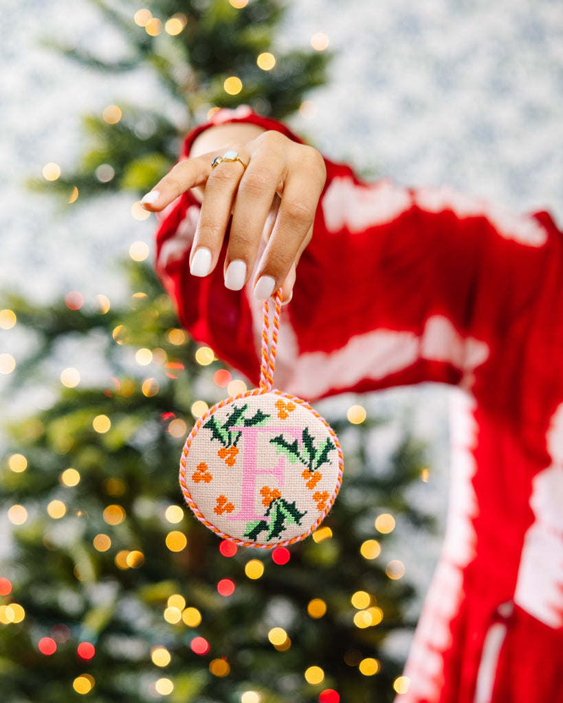 Person holding a Christmas ornament with a tree in the background