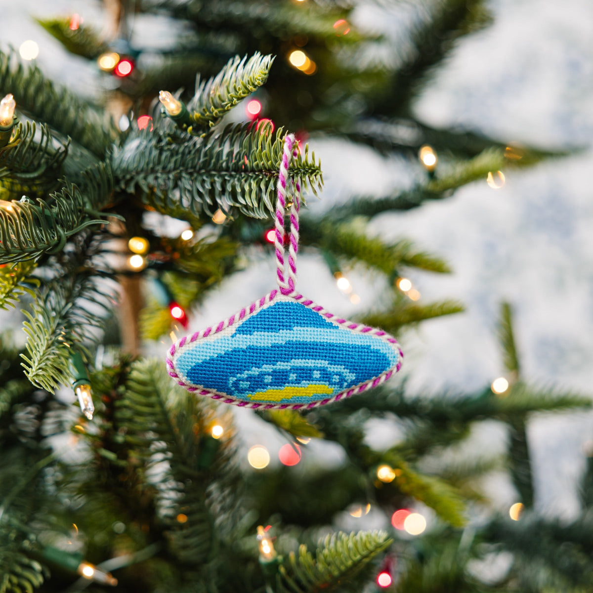 Decorative ornament on a Christmas tree with blurred lights in the background