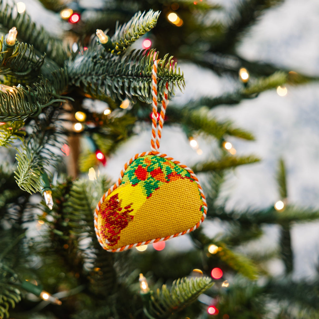 Decorative taco ornament on a Christmas tree with lights in the background