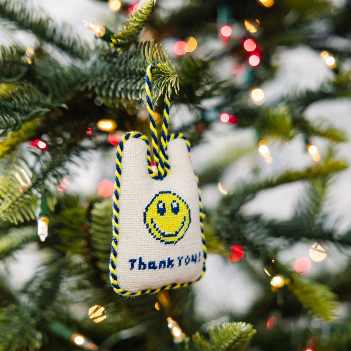 Decorative ornament with smiley face and 'Thank You' text on a Christmas tree.