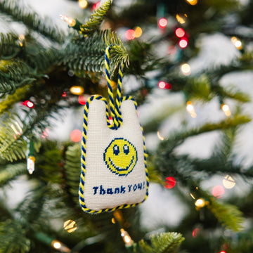 Decorative ornament with smiley face and 'Thank You' text on a Christmas tree.