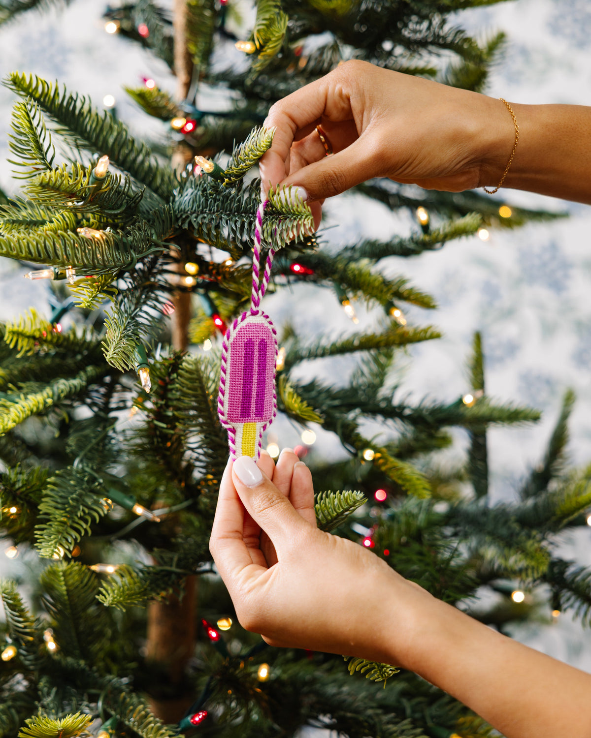 Person holding a pink and purple toy near a decorated Christmas tree.