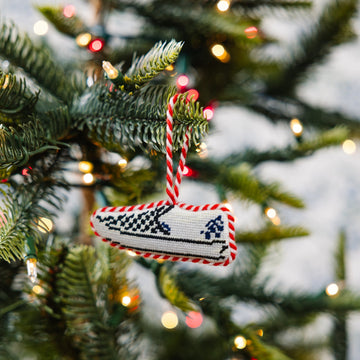 Decorative ornament with checkered pattern hanging on a Christmas tree.