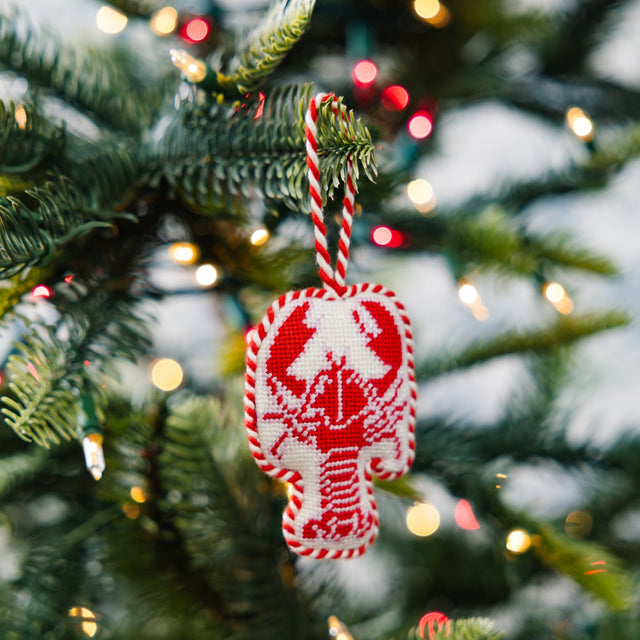 Red and white candy cane ornament on a Christmas tree with blurred lights in the background