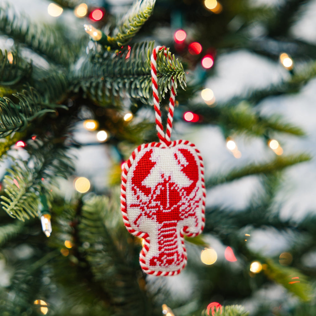 Red and white candy cane ornament on a Christmas tree with blurred lights in the background