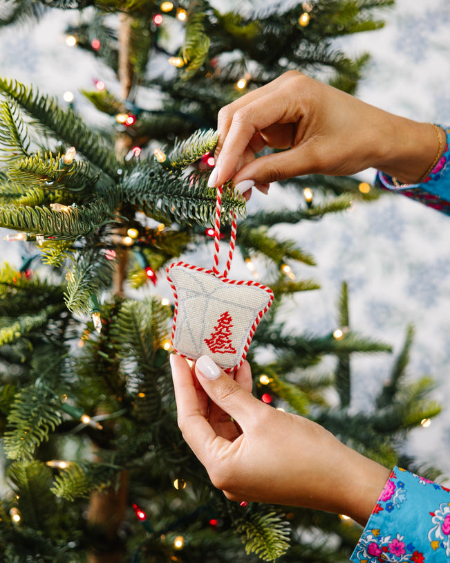 Person decorating a Christmas tree with a small ornament.