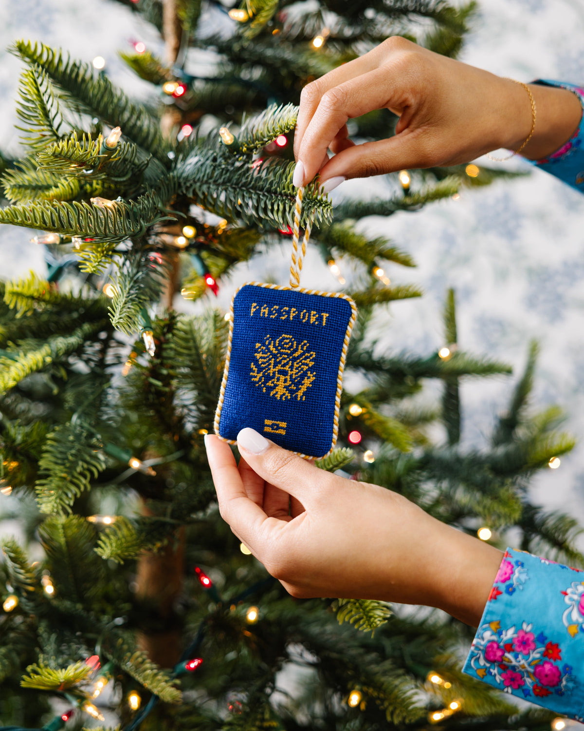 Passport-shaped ornament being hung on a Christmas tree
