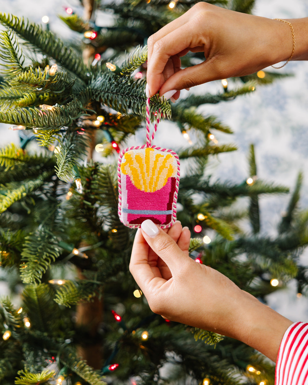 Person holding a Christmas ornament with a tree in the background
