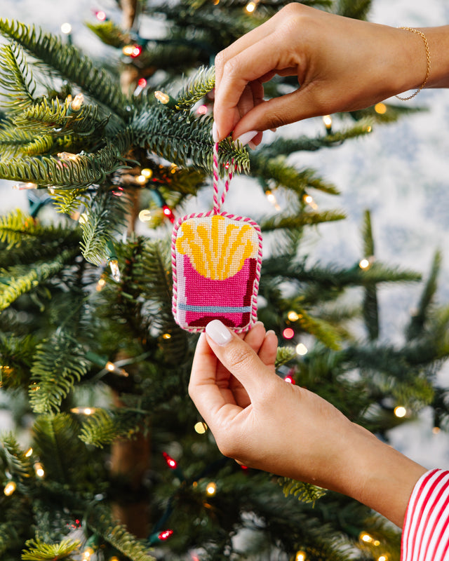 Person holding a Christmas ornament with a tree in the background