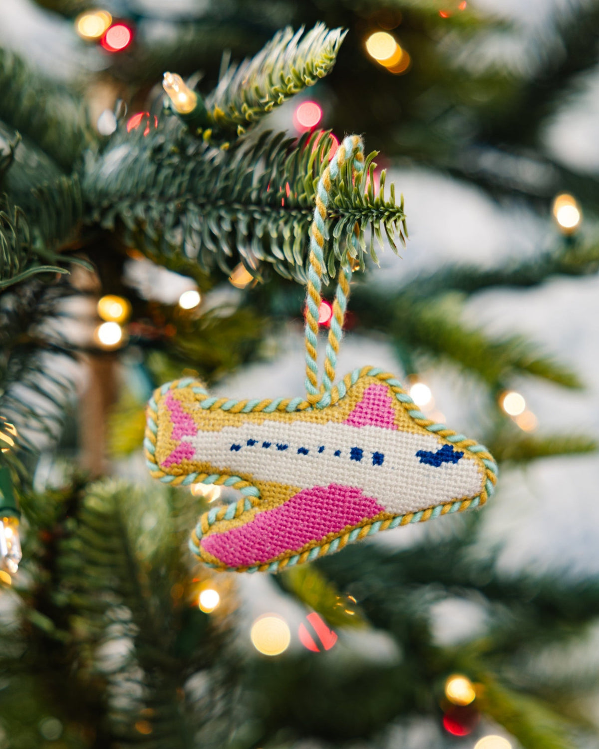 Decorative airplane ornament on a Christmas tree with lights in the background
