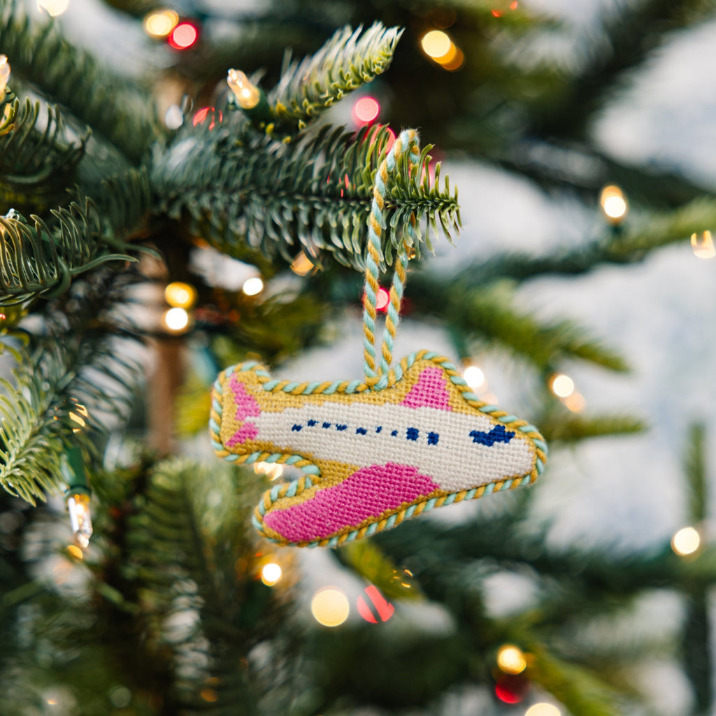 Decorative airplane ornament on a Christmas tree with lights in the background
