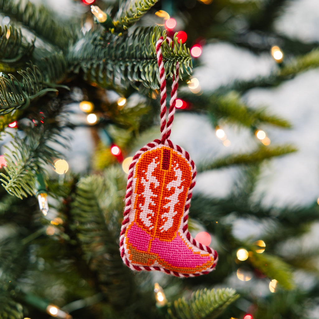 Colorful knitted boot ornament hanging on a Christmas tree.