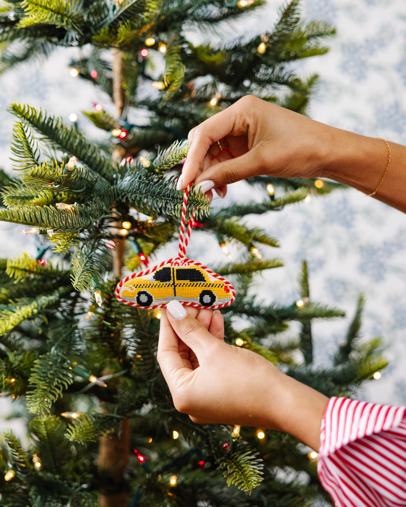 Person decorating a Christmas tree with a taxi ornament.