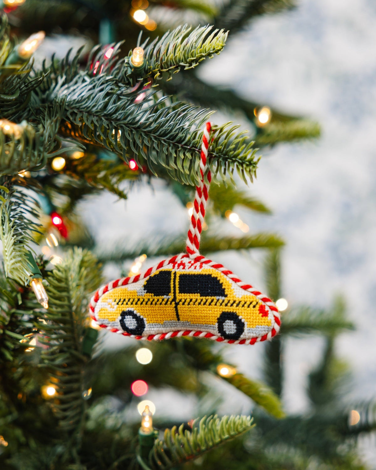 Decorative Christmas ornament shaped like a taxi on a Christmas tree with lights.