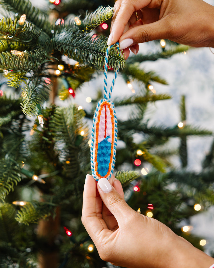 Hand holding a colorful ornament against a Christmas tree background