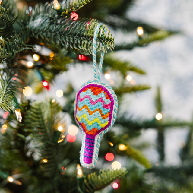 Colorful racket-shaped ornament on a Christmas tree with blurred lights in the background