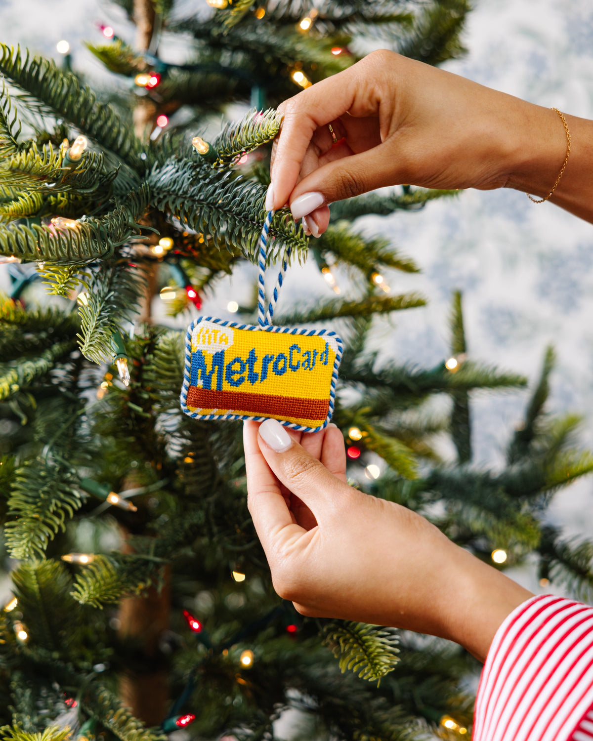 Hand holding a small card with 'MetroCard' printed on it against a Christmas tree background