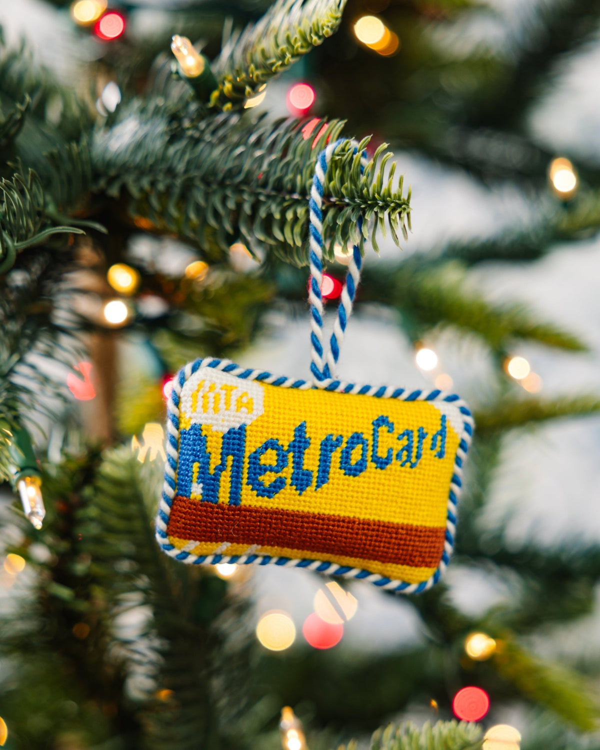 Decorative MetroCard ornament on a Christmas tree with lights in the background