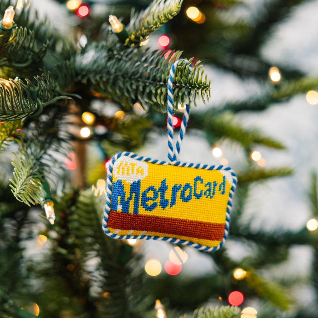 Decorative MetroCard ornament on a Christmas tree with lights in the background
