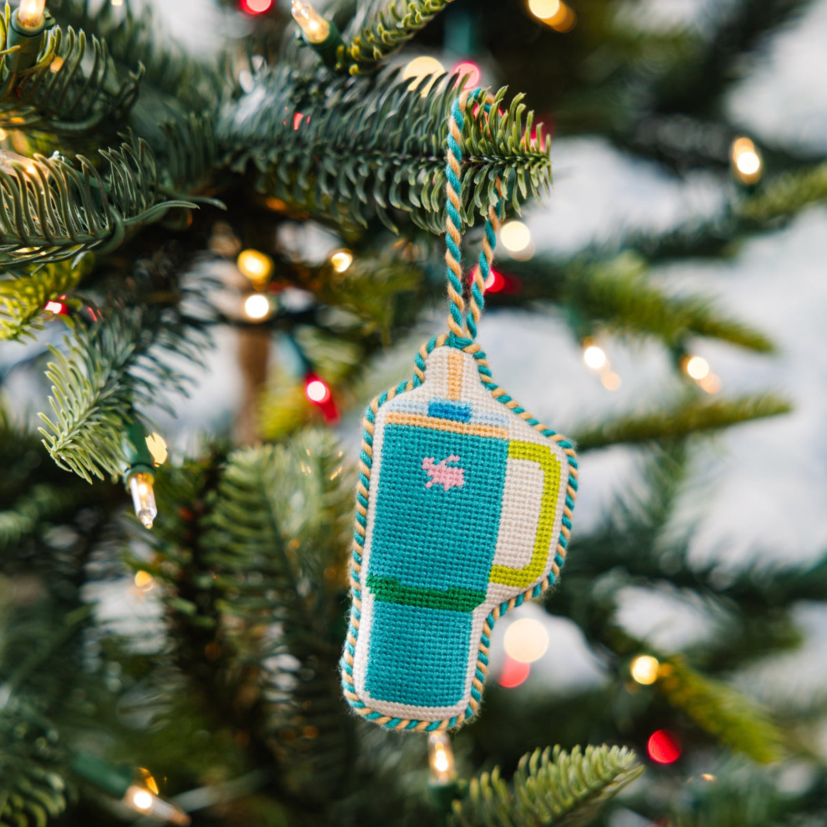 Decorative ornament on a Christmas tree with lights in the background
