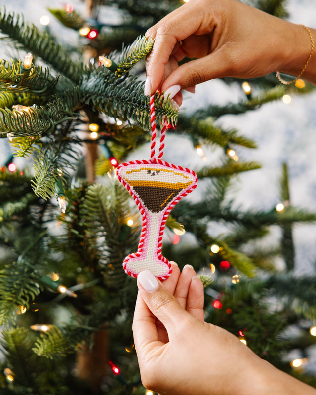 Hand holding a martini glass ornament on a Christmas tree