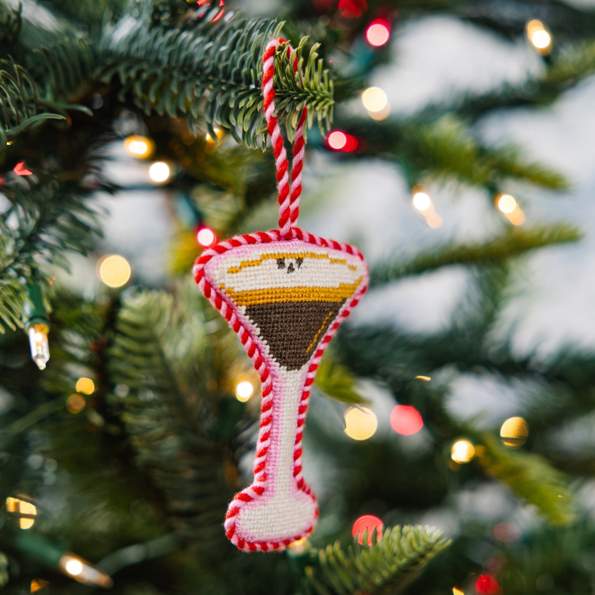 Decorative sand timer ornament on a Christmas tree with blurred lights in the background