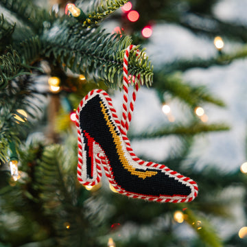 Decorative high-heeled shoe ornament on a Christmas tree with blurred lights in the background