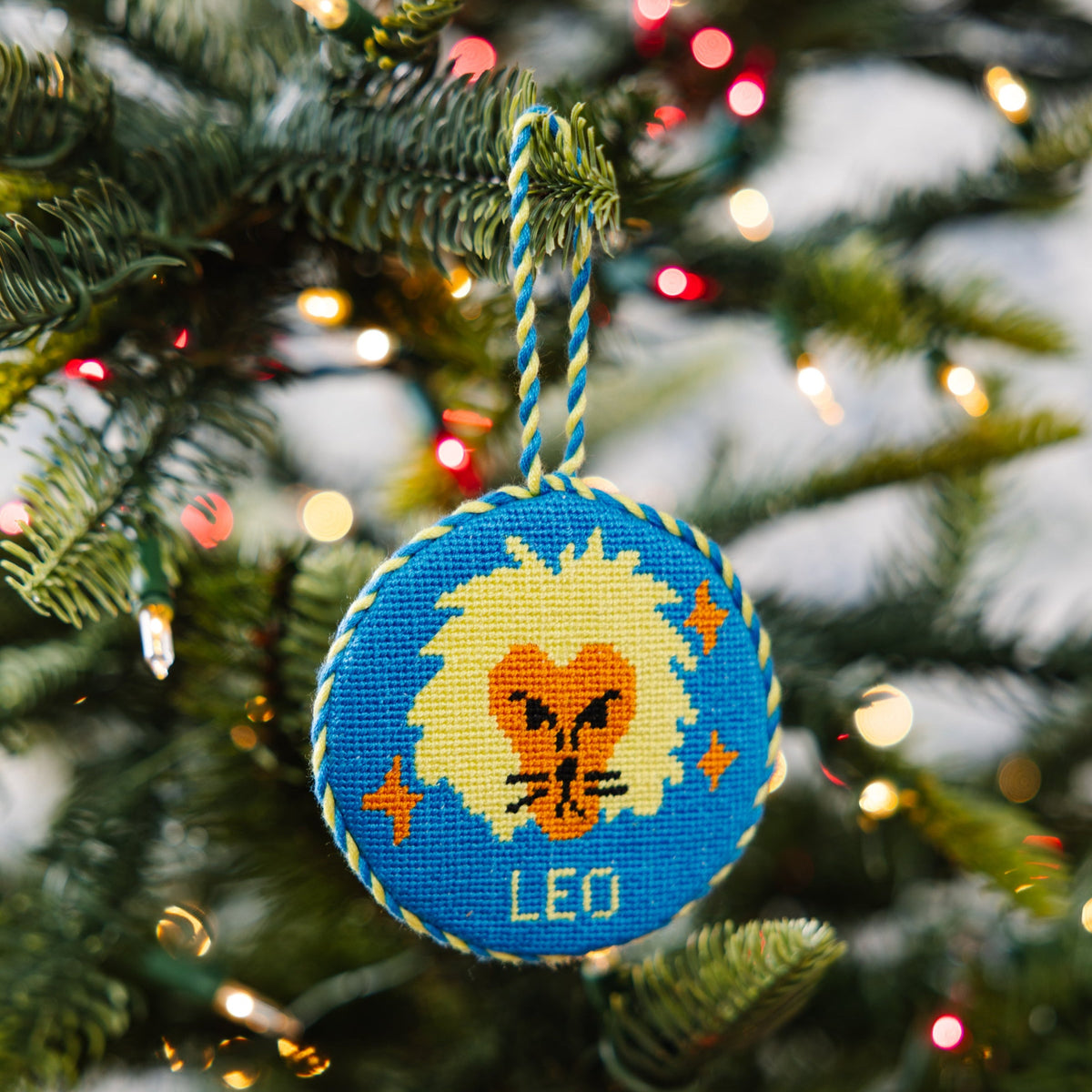 Decorative ornament with a lion design and 'Leo' text on a Christmas tree.