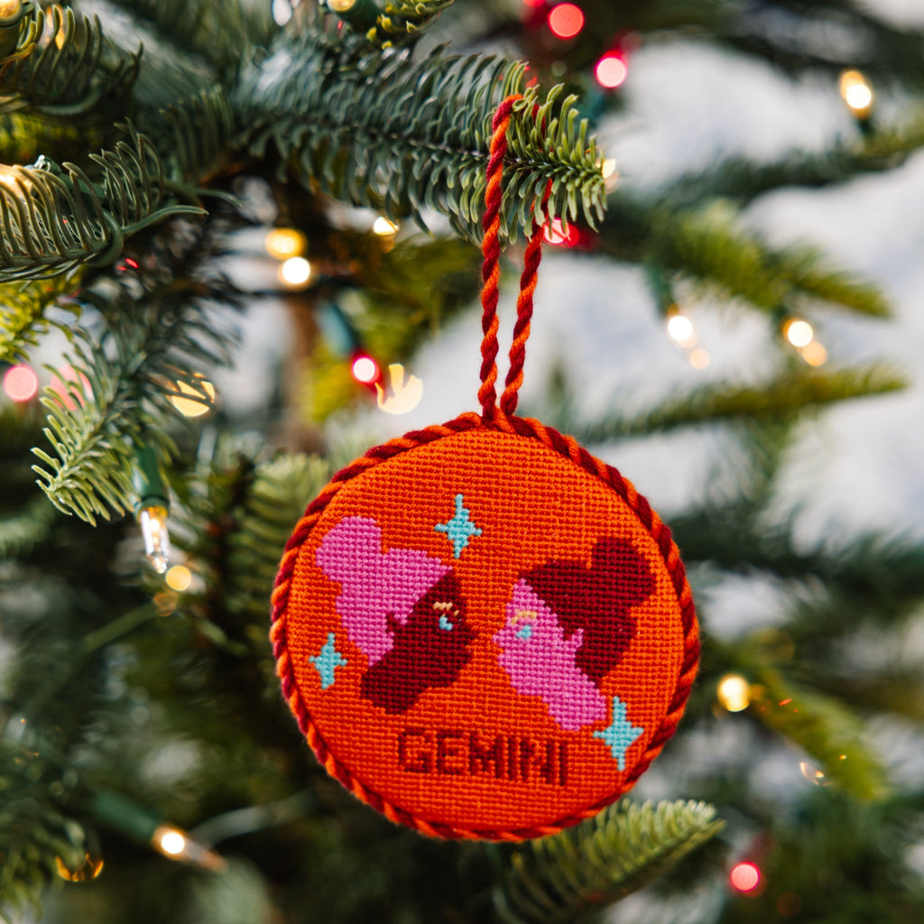Decorative ornament with 'Gemini' text and zodiac symbols on a Christmas tree.