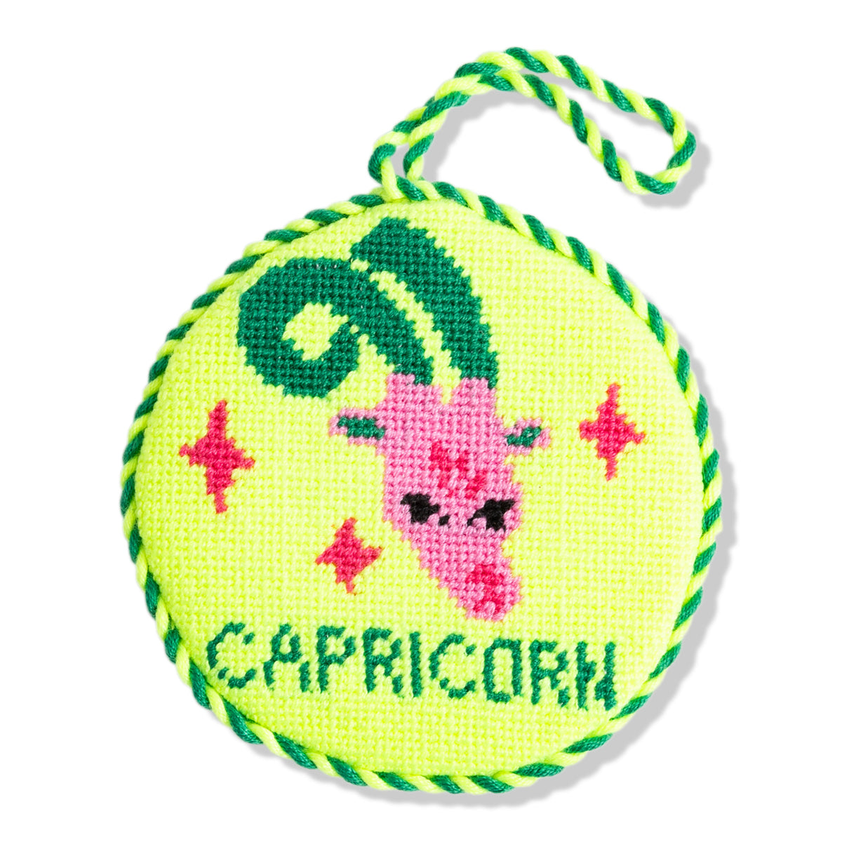 Round green fabric patch with Capricorn design and pink goat illustration on a white background