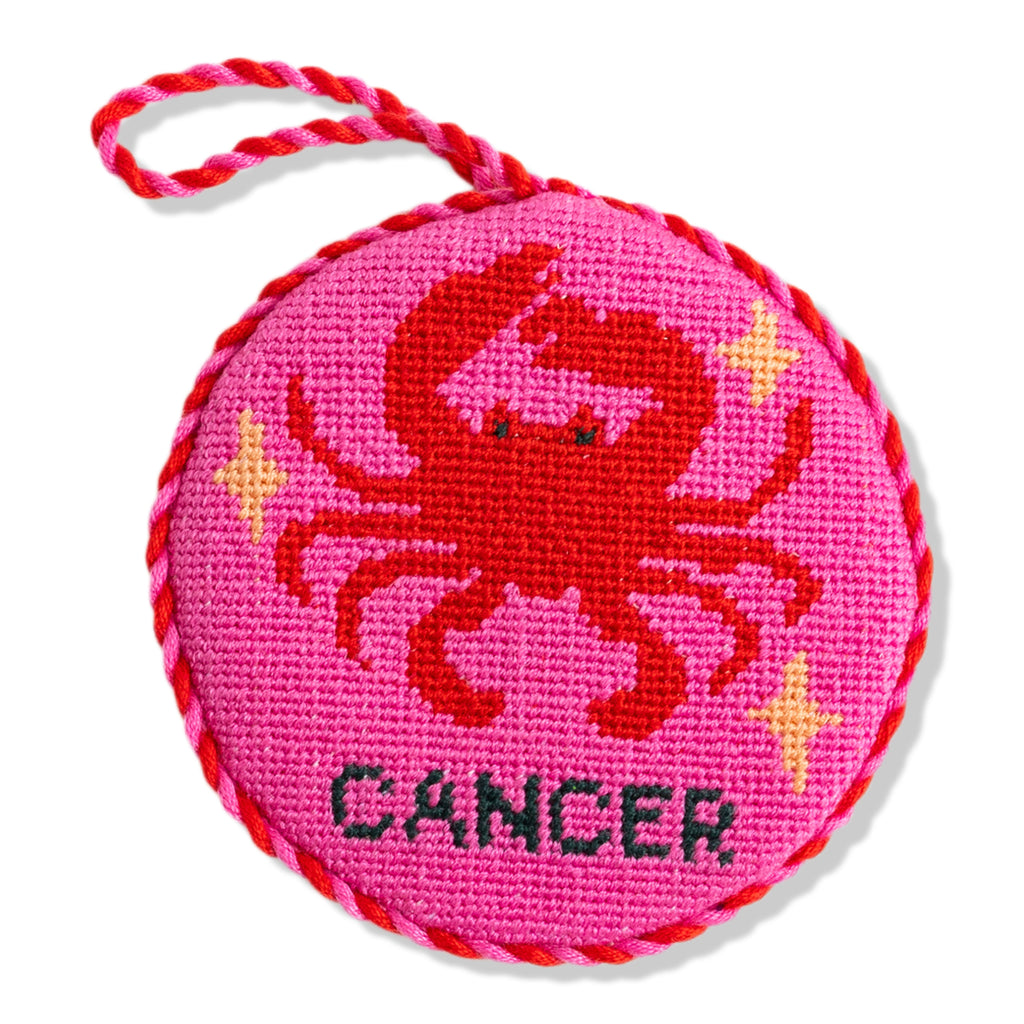 Circular pink object with a crab design and 'Cancer' text on a white background