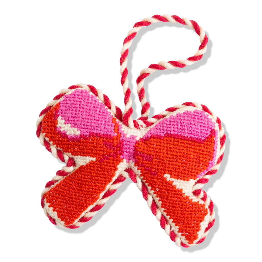Decorative bow-shaped ornament with red, pink, and white colors on a white background