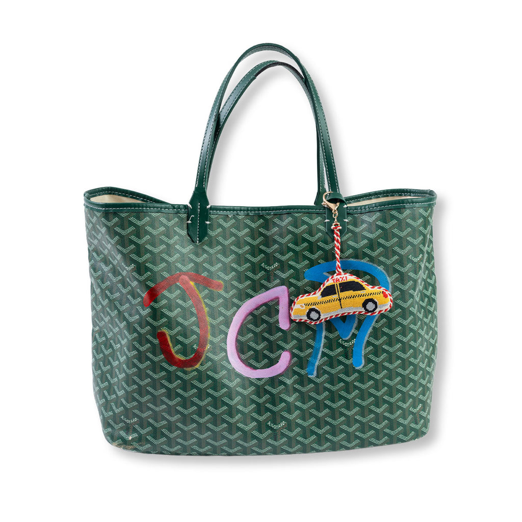 Green handbag with colorful embroidered design on a white background