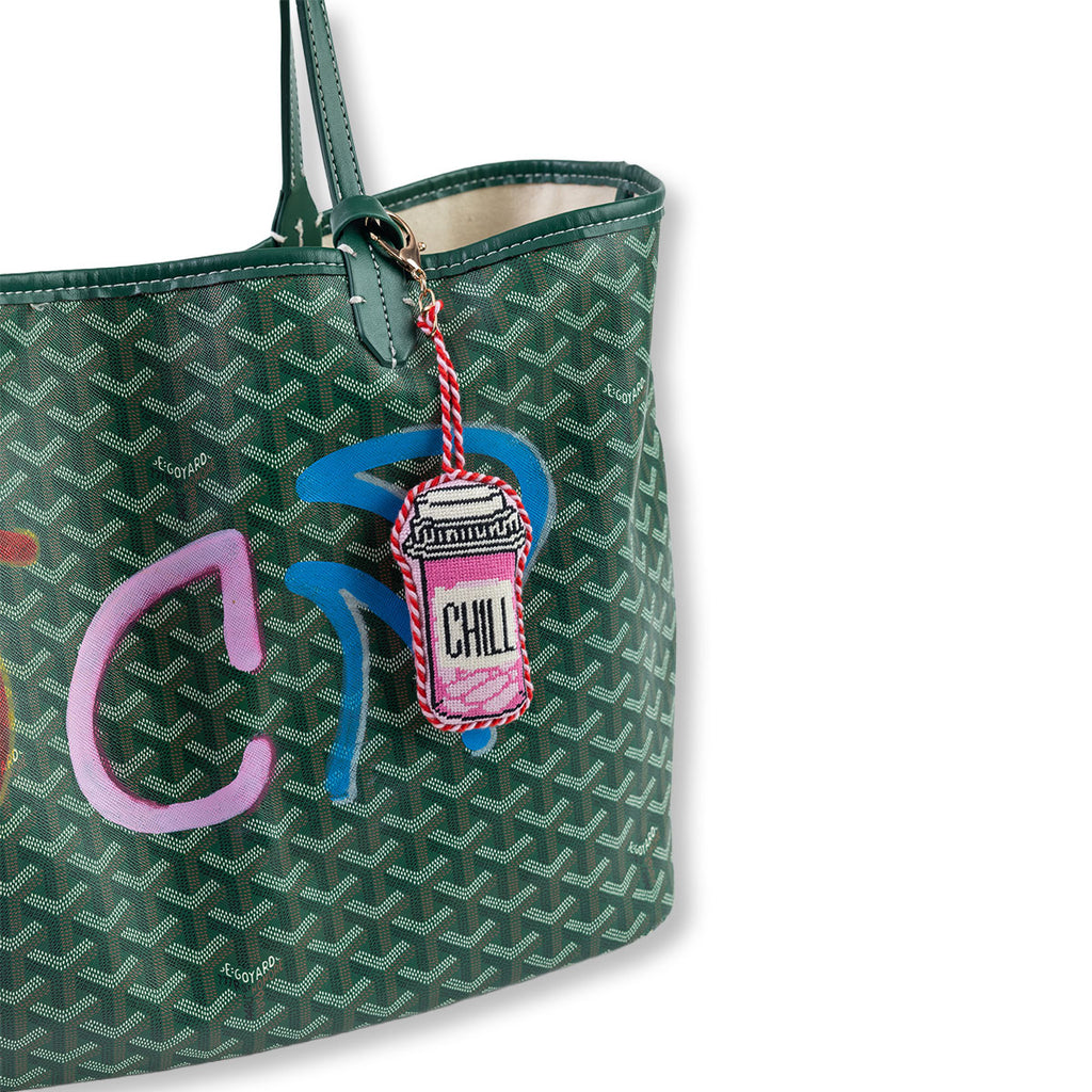 Green patterned tote bag with a colorful charm on a white background